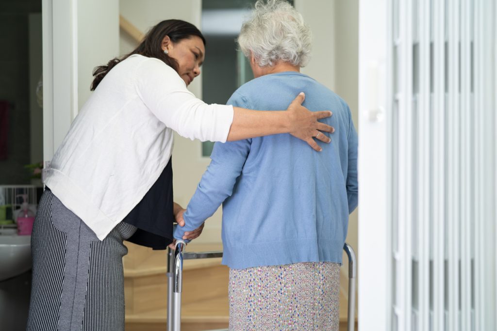 caregiver helps client with walker