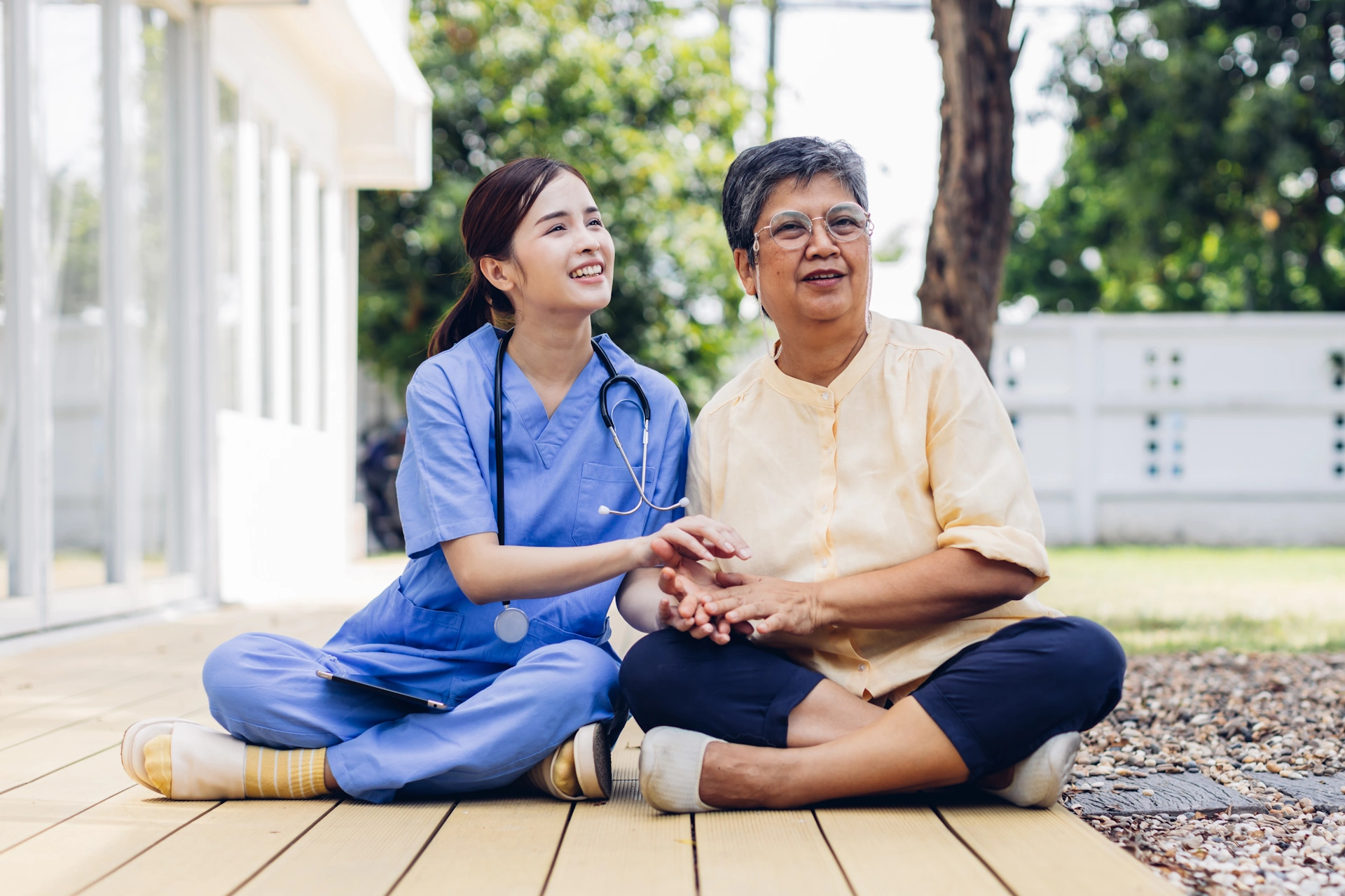 Rancho San Diego CA home care Asian caretaker sits on ground with Hispanic elderly woman