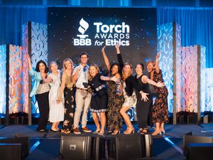 Happy Team Celebrating earning the BBB Torch Award for Ethics with funny faces and arms.